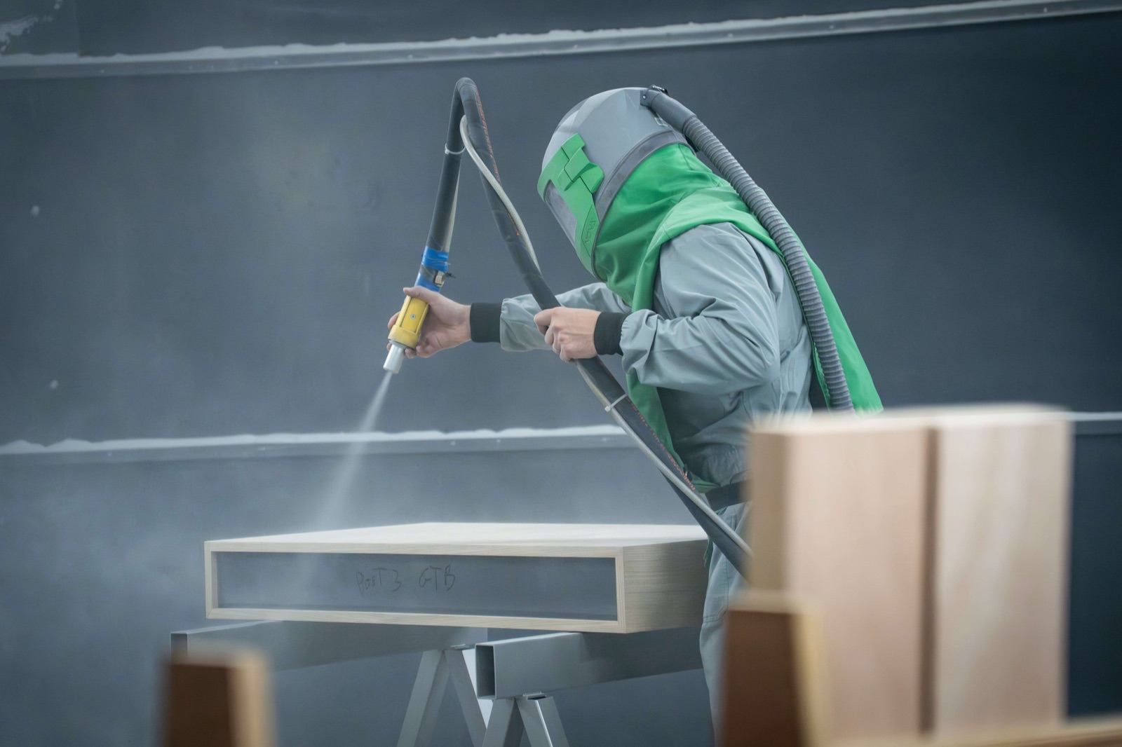 Straler van Sablé parelstraalt een houten werkstuk in de cabine